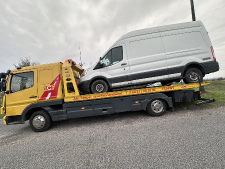 Fehér Ford kisteherautó sárga autómentő platóján