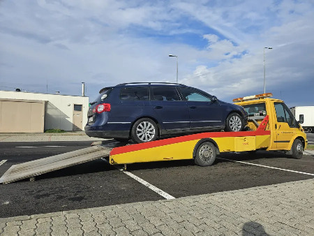 Kék kombi személyautó a rámpás autómentő platóján